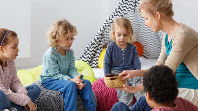 Teacher with several young children gathered around